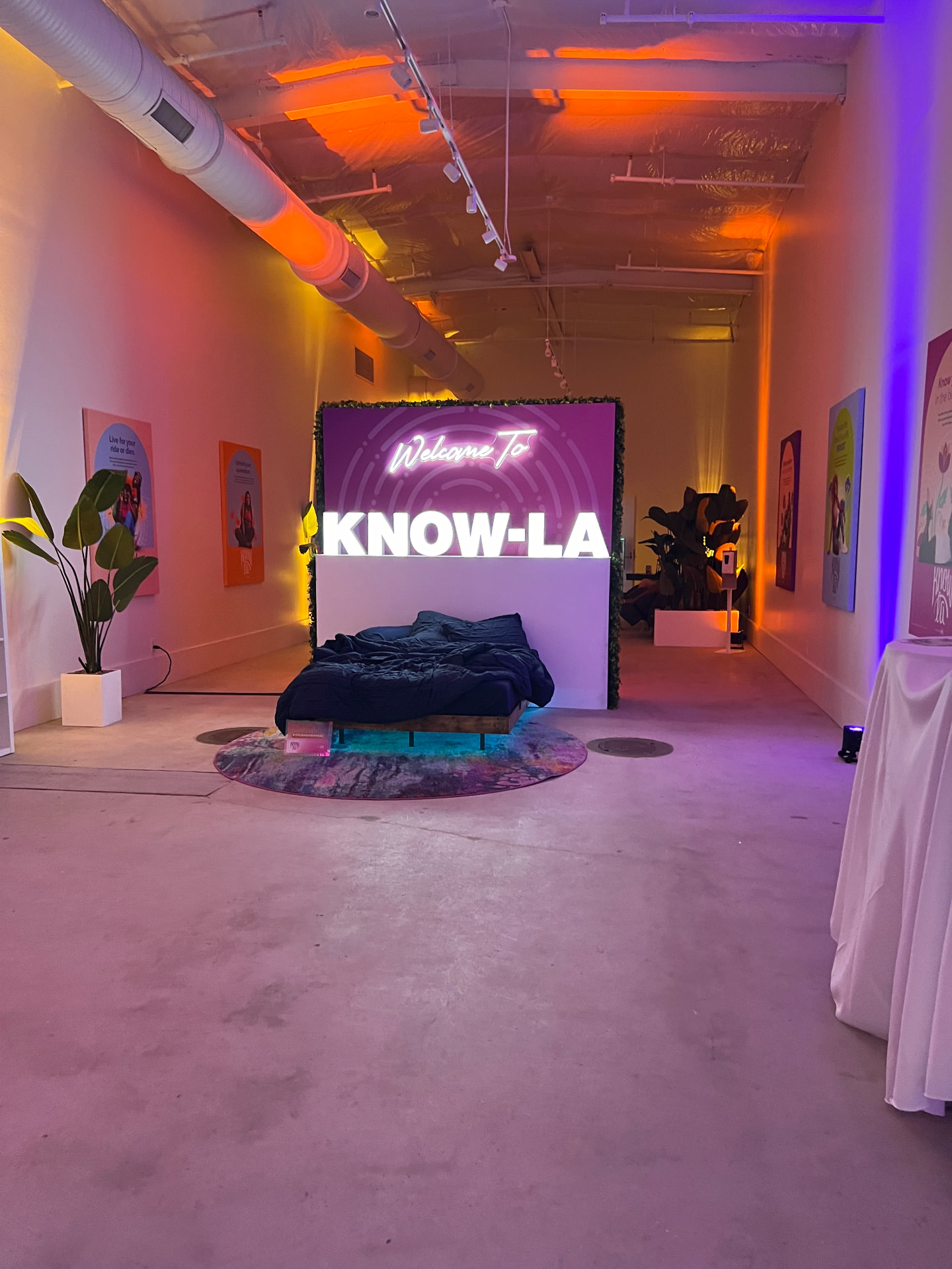 Custom KNOW-LA brand activation with a bedroom-themed installation, neon signage and dramatic colored lighting