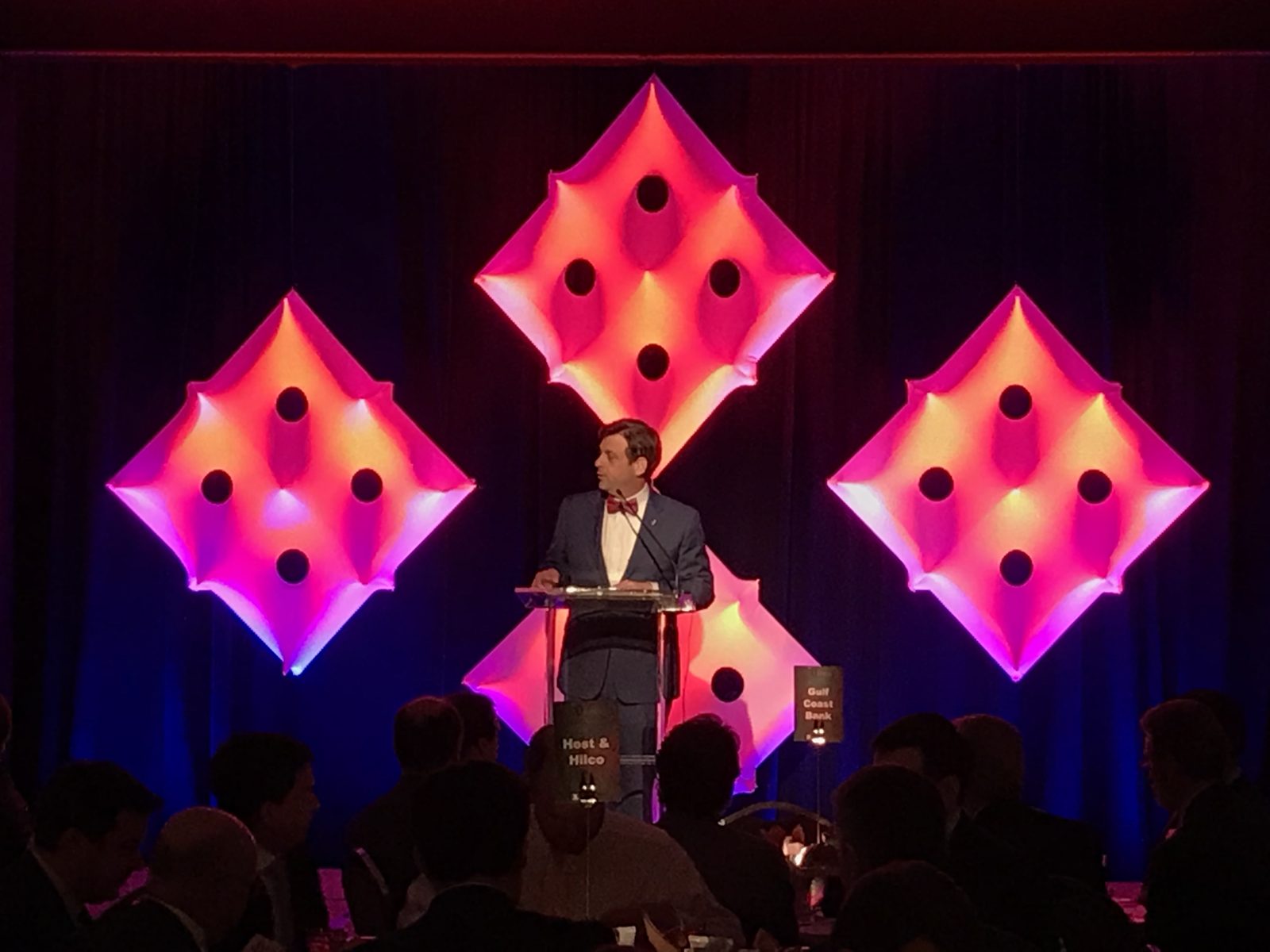 Custom scenic diamond panels lit in pink behind a keynote lectern