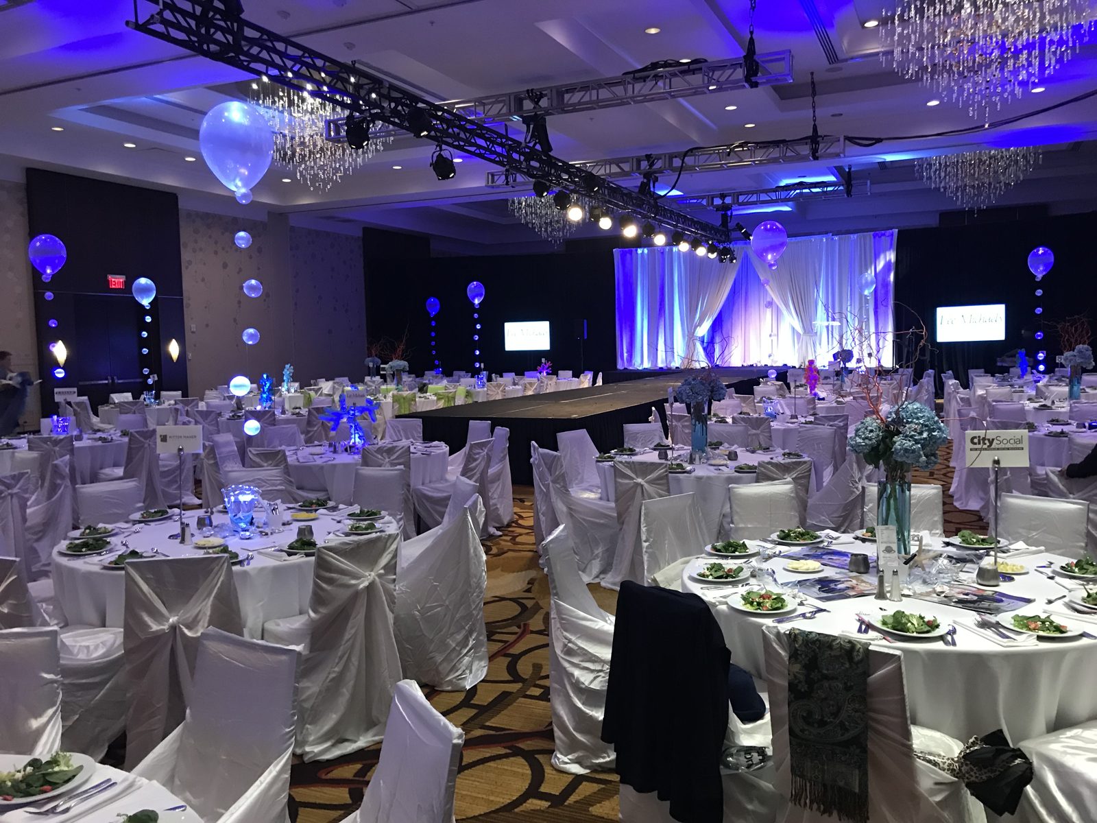Elegant gala ballroom with staging, chandeliers and blue accent lighting