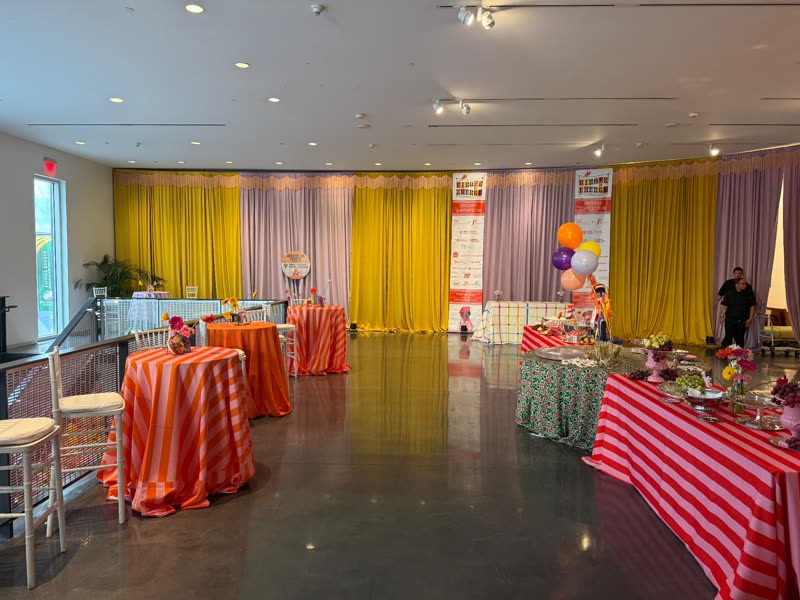 Chartreuse and lavender pipe-and-drape wall with fringe valance framing a colorful gala reception