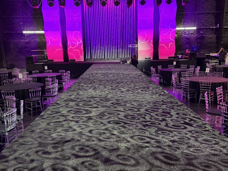 Runway stage framed by pink-lit pipe and drape panels